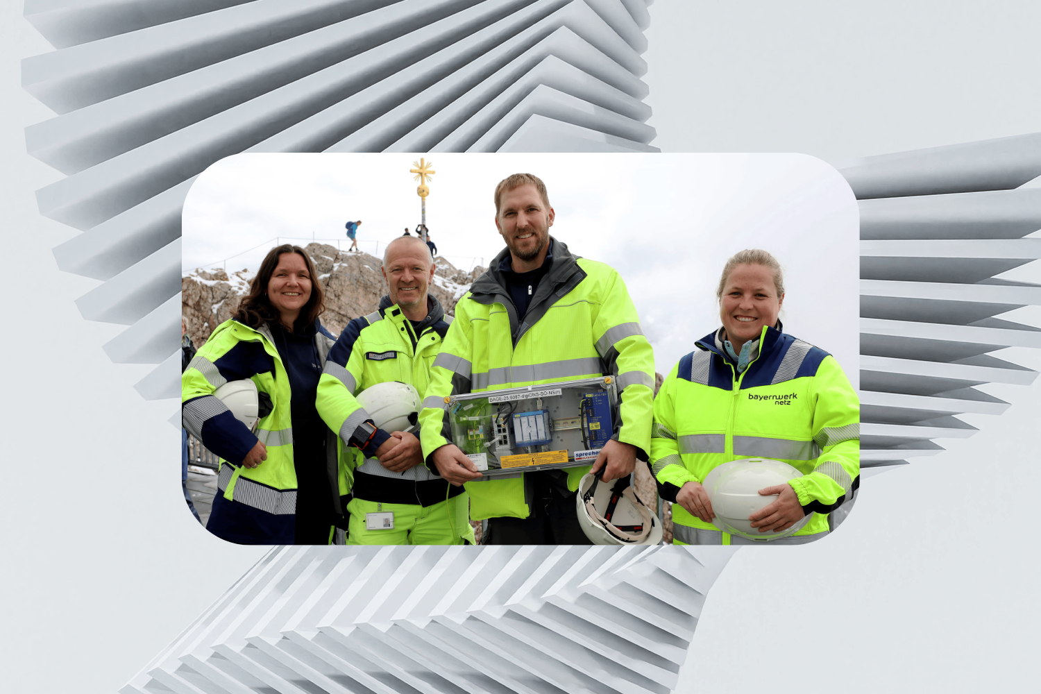 Ein vierköpfiges Team von Bayernwerk steht auf dem Gipfel der Zugspitze und hält eine Nachrüstbox für die Einführung von LTE-450 in den Händen.